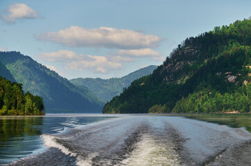 Naklejka na ściany i meble The boat cuts the surface of the lake water of Lake Teletskoye, Altai Republic, Russia.