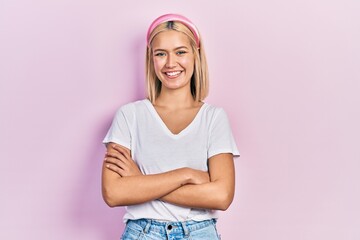 Beautiful blonde woman wearing casual white t shirt happy face smiling with crossed arms looking at the camera. positive person.