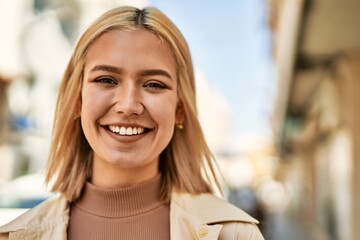 Young blonde girl smiling happy standing at the city.