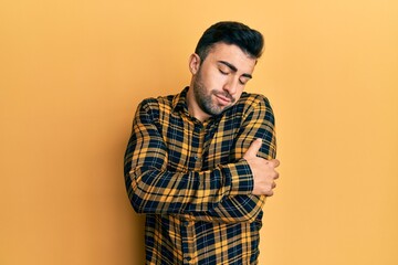 Young hispanic man wearing casual clothes hugging oneself happy and positive, smiling confident. self love and self care