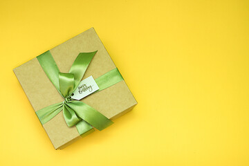 Craft gift box with green bow and happy birthday lettering on yellow