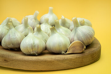 Garlic on a wooden tray on a yellow background