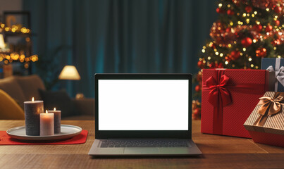 Laptop with blank screen, gifts and Christmas tree