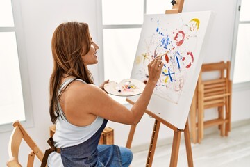 Young hispanic artist woman smiling happy drawing at art studio.
