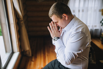 A handsome, stylish man, businessman in a white shirt sits on the couch, worrying about problems at work.