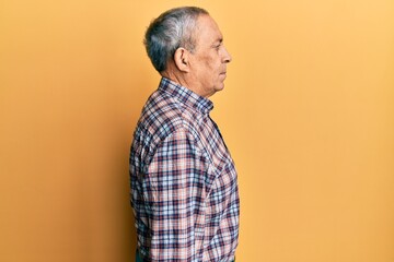 Handsome senior man with grey hair wearing casual shirt looking to side, relax profile pose with...
