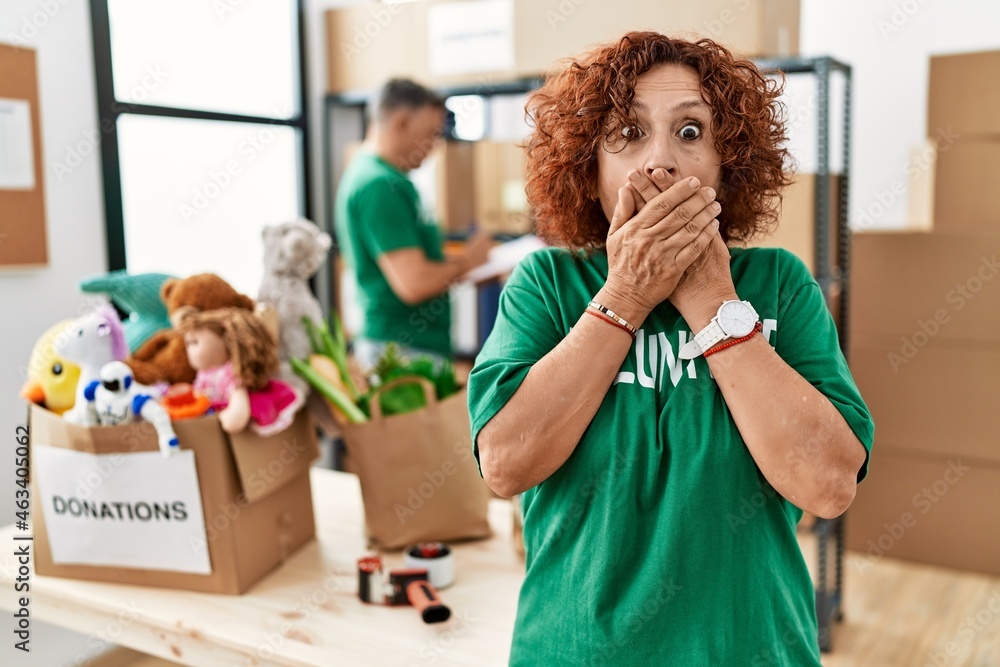 Sticker Middle age woman wearing volunteer t shirt at donations stand shocked covering mouth with hands for mistake. secret concept.