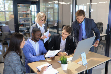 Five business people during a meeting sitting around a table.