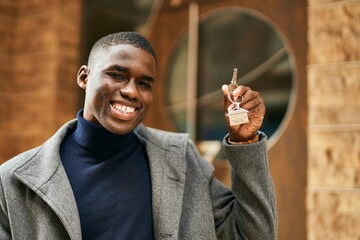Young african american man smiling happy holding new home key at the city