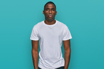 Young african american man wearing casual white t shirt puffing cheeks with funny face. mouth inflated with air, crazy expression.