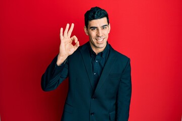 Handsome hispanic man wearing business clothes smiling positive doing ok sign with hand and fingers. successful expression.