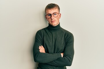 Young caucasian man wearing glasses with arms crossed gesture relaxed with serious expression on face. simple and natural looking at the camera.