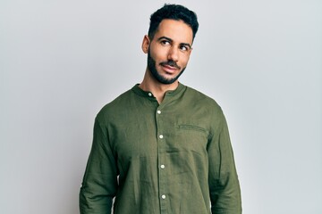 Young hispanic man wearing casual clothes smiling looking to the side and staring away thinking.