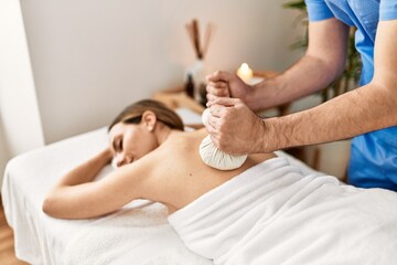 Obraz na płótnie Canvas Young woman reciving herbal pouches thai massage at beauty center.