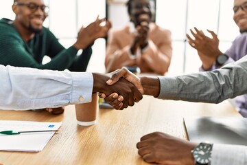 Group of african american business workers smiling and clapping to partners handshake at the office.