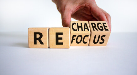 Refocus and recharge symbol. Businessman turns cubes and changes the word 'refocus' to 'recharge'. Beautiful white table, white background. Business refocus and recharge concept. Copy space.