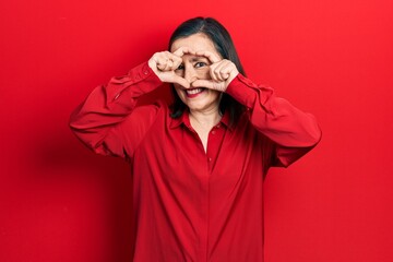 Middle age hispanic woman wearing casual clothes doing heart shape with hand and fingers smiling looking through sign