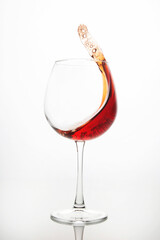 red wine splashes out of a glass on a light background. alcoholism and addiction. drinks for the holiday