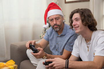 un père de famille joue à la console de jeux vidéos avec son fils. Ils ont des manettes entre les mains et ils s'amusent, c'est fun