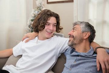 Un père de 50 ans passe un bon moment agréable avec son fils à Noël ils sont assis dans le...