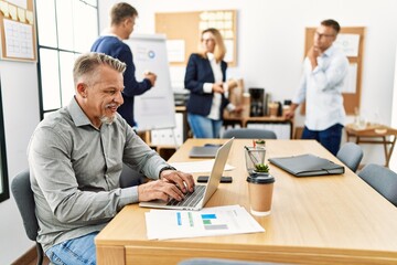 Middle age business worker smiling happy working while partners have break time at the office.