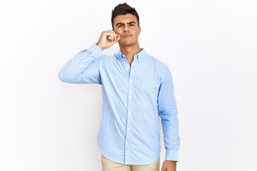 Young hispanic man wearing business shirt standing over isolated background mouth and lips shut as...