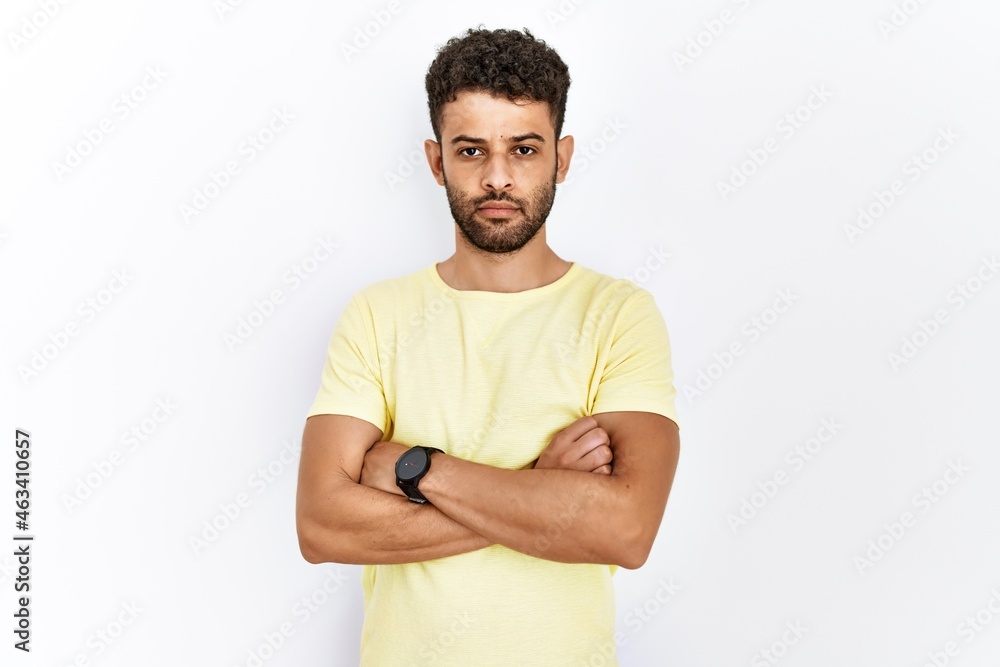 Poster Arab young man standing over isolated background relaxed with serious expression on face. simple and natural looking at the camera.