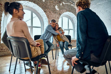 Relieved man and woman hugging giving psychological support empathy during a group therapy session,...