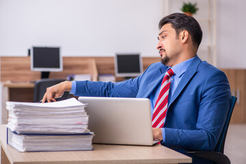 Young male employee unhappy with excessive work at workplace