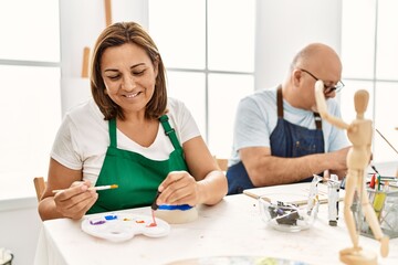 Obraz premium Middle age hispanic painter couple smiling happy painting at art studio.