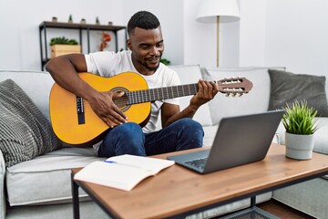 Young african american man smiling confident playing guitar at home