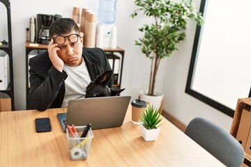 Young latin businessman overworked working at the office.