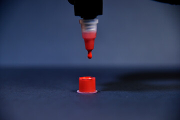 Red ink dripping in plastic cup.
