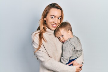 Young caucasian woman holding and hugging her son with love. Family of two bonding together. Mother holding infant toddler