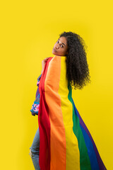 Mujer afroamericana en fondo amarillo con la bandera de la diversidad en su cuerpo