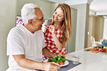 Middle age hispanic couple smiling happy eating beef with salad at the kitchen.