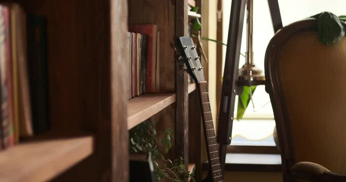 Guitar leaning on corner of wooden bookshelf
