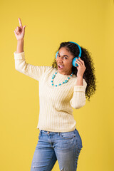 Mujer afroamericana alegre escuchando música y señalando arriba en fondo amarillo