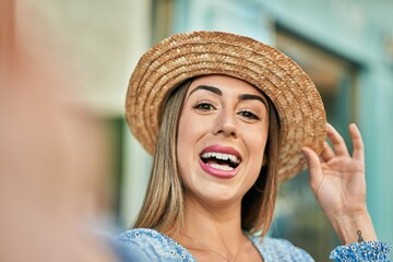 Young hispanic woman wearing miling happy  making selfie by the camera at the city.