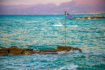 Aegean sea coastline with greek flag, Hersonissos, Crete, Greek