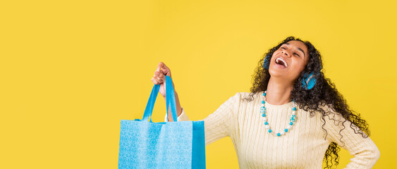 Panorámica de una mujer morena en fondo amarillo muy sonriente von una bolsa de compras ecológica 