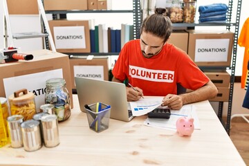 Handsome hispanic man working as volunteer doing countability at donation stand