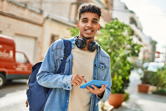 Hispanic young man using touchpad device at the street
