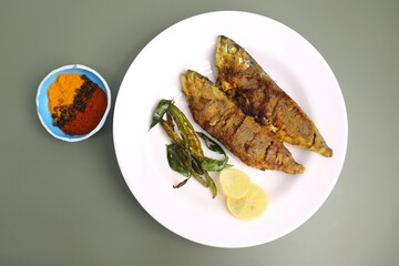 Indian Mackerel fish fry. Bangda Rava fry. whole Fried fish served on a banana leaf with fried chilies, lemon slices, and Indian spices. also known as talalele bangde in Marathi. Copy space.