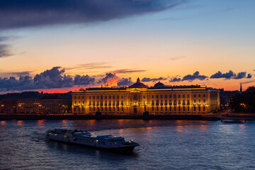 Illuminated Russian Academy of Arts in Saint Petersburg, Russia. Blurred drifting boat in the middle of river. Beautiful sunset landscape. Travel destination. Place for vacation. Wanderlust concept.