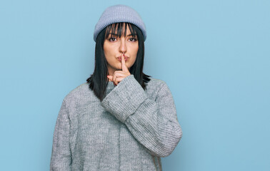 Young hispanic woman wearing cute wool cap asking to be quiet with finger on lips. silence and secret concept.