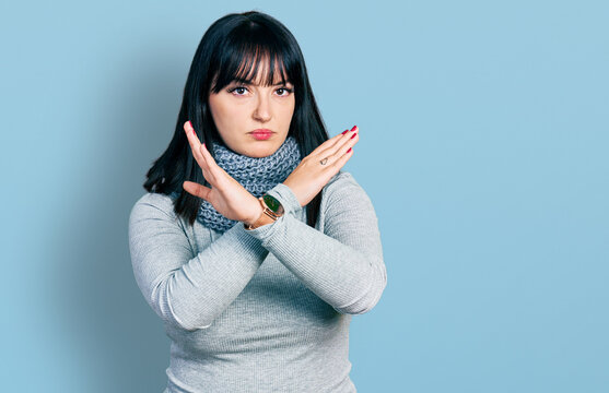 Young hispanic plus size woman wearing winter scarf rejection expression crossing arms and palms doing negative sign, angry face