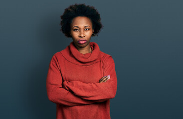 African american woman with afro hair wearing turtleneck sweater skeptic and nervous, disapproving expression on face with crossed arms. negative person.