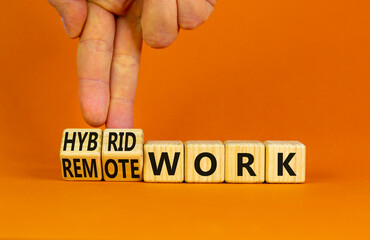 Hybrid or remote work symbol. Businessman turns cubes and changes words 'remote work' to 'hybrid work'. Beautiful orange background. Business, hybrid or remote working concept, copy space. - obrazy, fototapety, plakaty