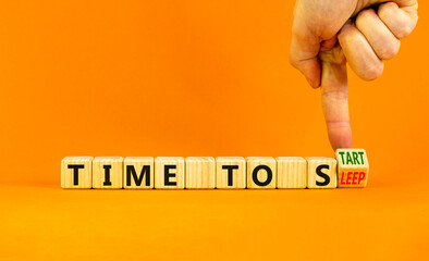 Time to sleep or start symbol. Businessman turns a wooden cube and changes words time to sleep to time to start. Beautiful orange background. Business and time to sleep or start concept, copy space